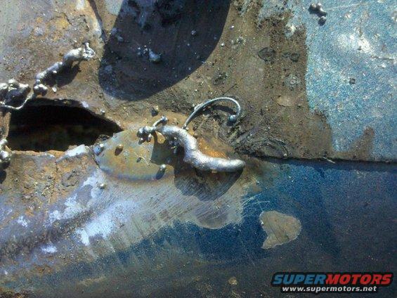 close-up of rusted metal with welding repairs, showing a blue painted surface underneath