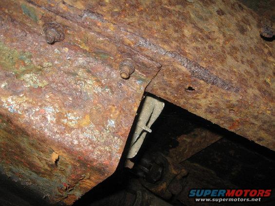 Rusted metal frame with bolts, showing significant corrosion and some green paint remnants