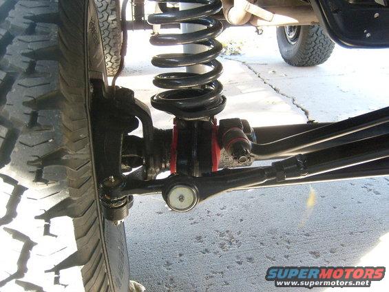 Close-up of a vehicle's front suspension with large tire and black coil spring