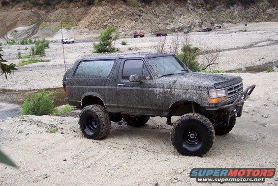 Mud-covered 1995 Ford Bronco with off-road tires and custom bumper