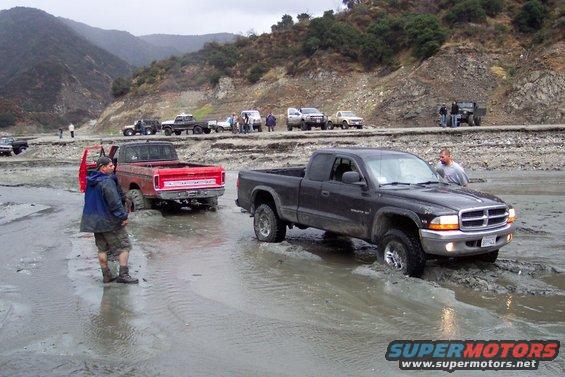 Black Dodge Dakota pickup truck in mud, front view. License plate visible