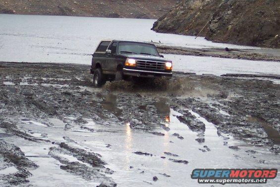 Dark green 1995 Ford Bronco driving through mud
