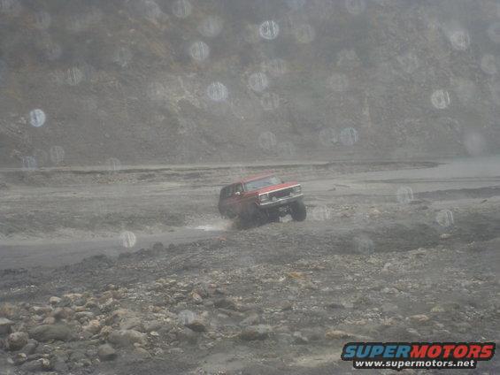 red SUV driving on a dirt road with mountains in the background