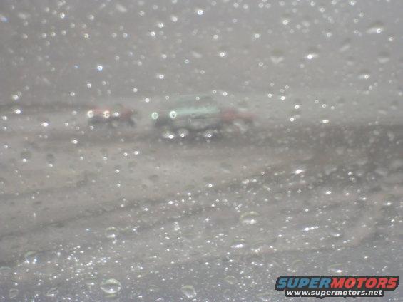 Two vehicles seen through a rain-streaked windshield