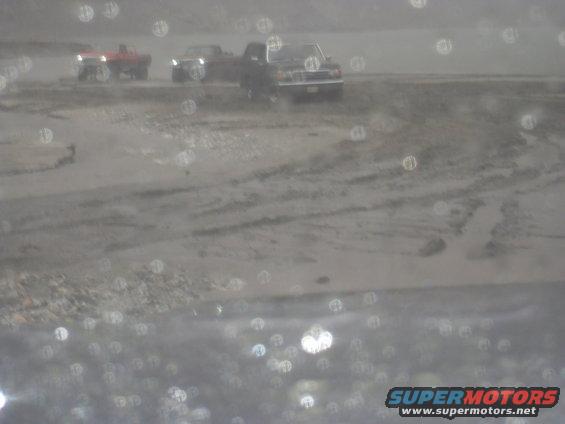 Several pickup trucks are parked in a muddy, outdoor area. The image has many out-of-focus circles