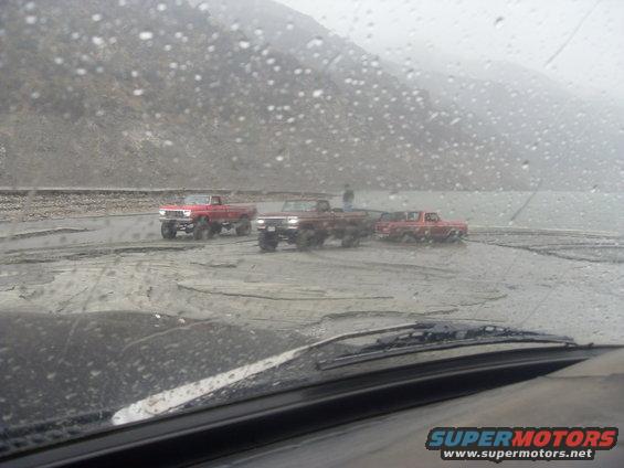 three trucks stuck in mud, view from inside a vehicle