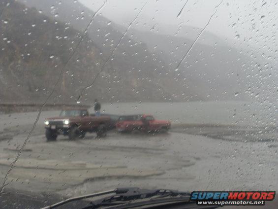 Two trucks in a muddy, rainy landscape
