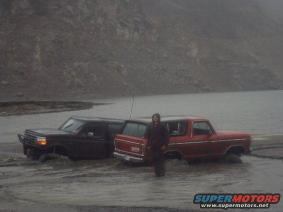 Red 1979 Ford Bronco and black SUV stuck in mud