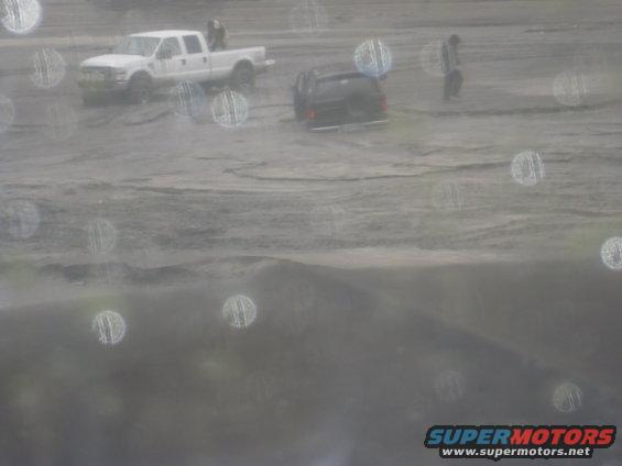 White pickup truck and black SUV in muddy terrain