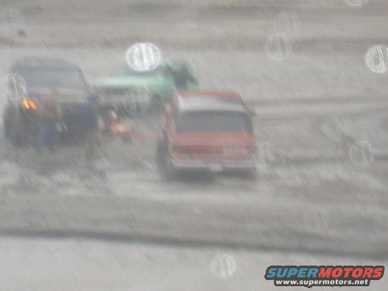 Red SUV from rear, with blue SUV and green truck behind in a blurry scene