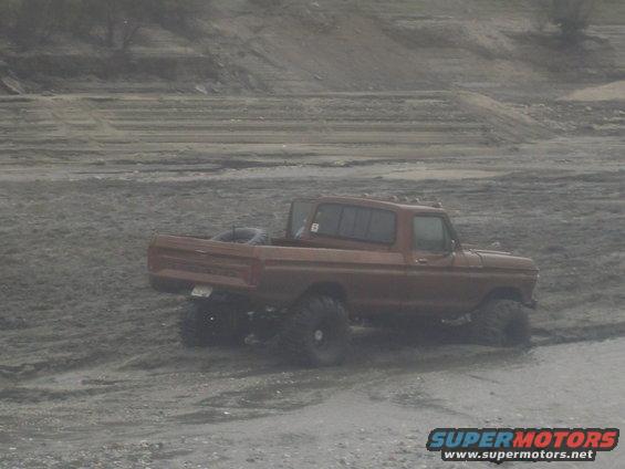 Brown pickup truck with large tires on muddy ground