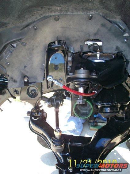 close-up of vehicle suspension parts, black painted metal, red hose, green ring, date stamp 11/21/2010