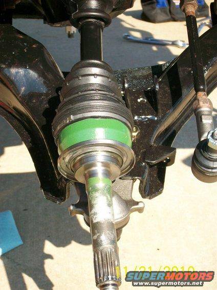 Close-up of a CV axle with a green boot, part of a vehicle's suspension system