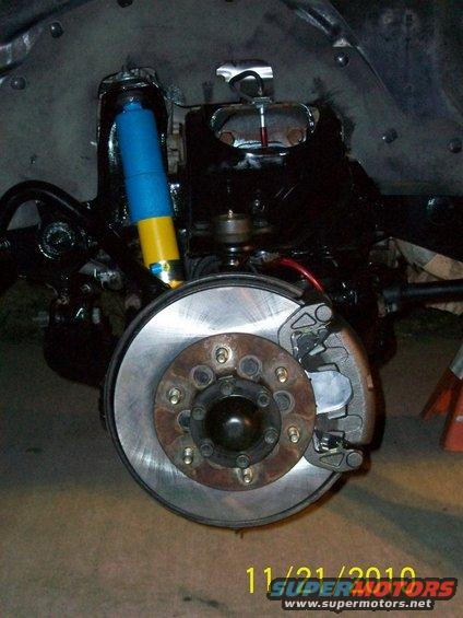 Vehicle brake rotor and caliper with a blue and yellow shock absorber