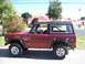 1970 Ford Bronco - A red 1970 Ford Bronco is parked outside on a sunny day with a girl in the driver's seat.