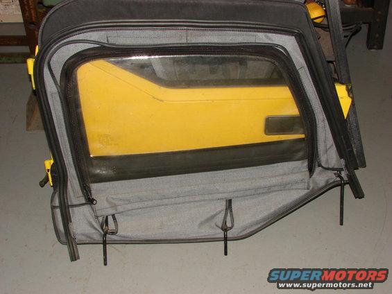 Yellow Jeep door with soft top window removed, showing grey fabric and black zippers
