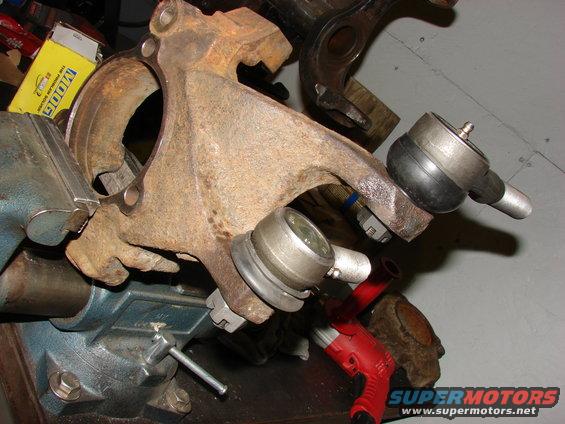 Rusted suspension parts, including ball joints and a spindle, held in a vise