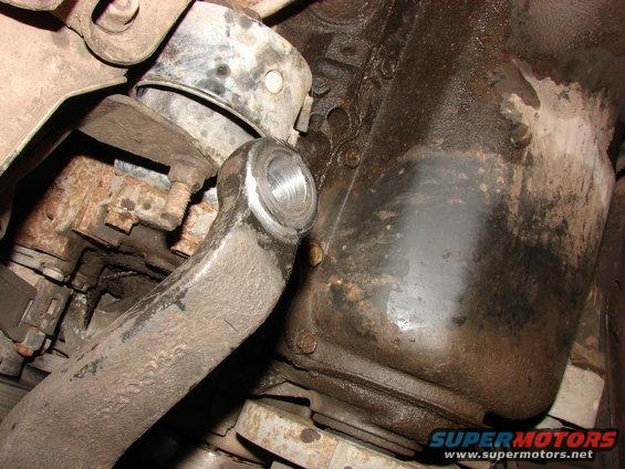 close-up of a greasy suspension part bolted to a rusty engine block