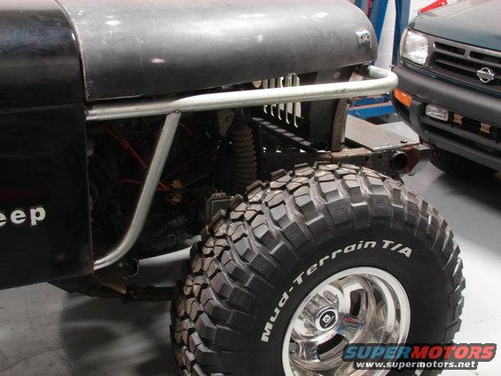 Jeep fender with "eep" visible, large Mud-Terrain T/A tire on chrome rim, and part of a green SUV in background