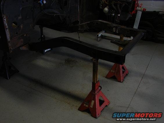 Vehicle frame on red jack stands in garage