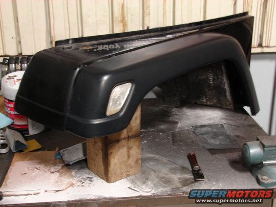 Black Jeep fender flare on a workbench with tools and supplies