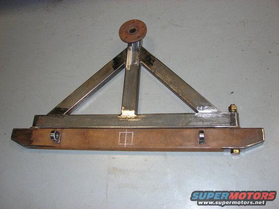 Custom fabricated tire carrier with a triangular frame and a horizontal bumper section, showing welds and bolt attachments