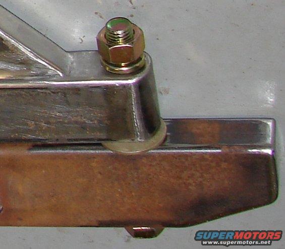 Close-up of a metal bracket with a bolt and nut, showing Supermotors.net logo