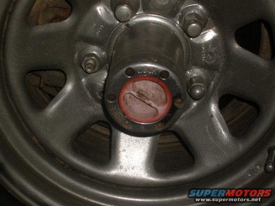 Close-up of a metal wheel hub with red locking mechanism. Text 'LOCK' is visible