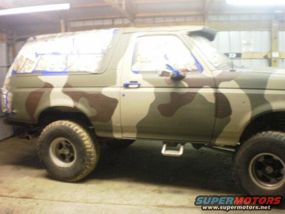 Side view of a 1995 Ford Bronco with camouflage paint and blue masking tape on windows