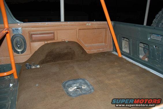 Interior cargo area with orange roll cage and brown carpet