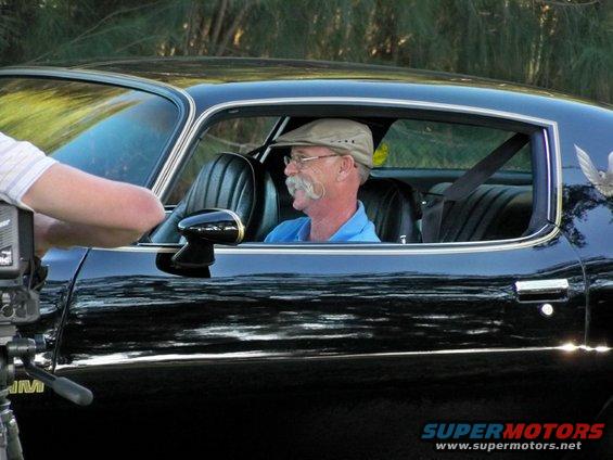 Side view of a black 1977 Pontiac Trans Am with a man driving