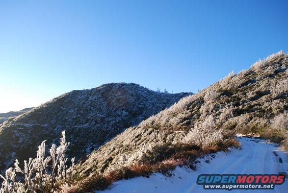 Snowy road winds up a mountain covered in frost