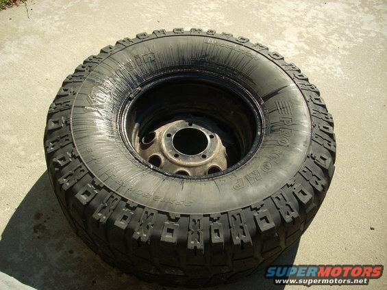 Off-road tire mounted on a metal rim, resting on concrete