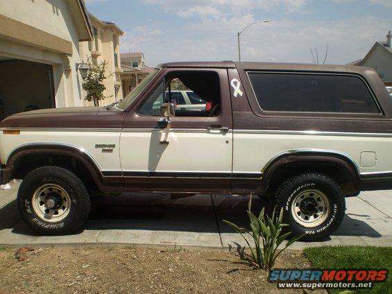 Brown and white Ford Bronco parked on a driveway, side view
