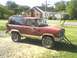 1986 Ford Bronco II - Red 1986 Ford Bronco II parked outdoors with a flat front tire and a jack under the bumper.