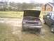 1986 Ford Bronco II - A red SUV sits in a muddy lot with its hood open, next to a black pickup truck.