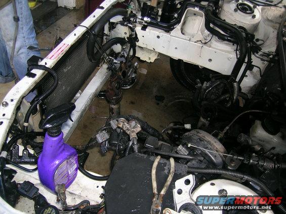 Engine bay with radiator, wiring, and tools. A purple spray bottle is visible