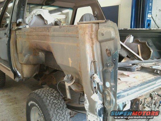 rusted rear quarter panel and wheel well of a vehicle undergoing repair