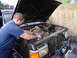 1985 Ford Bronco - A man works on the muddy engine of a truck, which appears to be from the early 1980s.