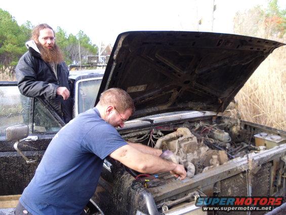 1985 Ford Bronco engine bay with two men working on it