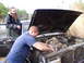 1985 Ford Bronco - Two men attend to the engine of a muddy 1985 Ford Bronco.