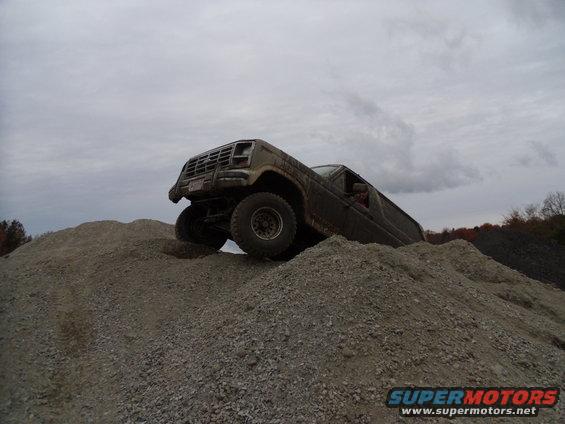 Brown off-road vehicle with large tires climbing a gravel hill
