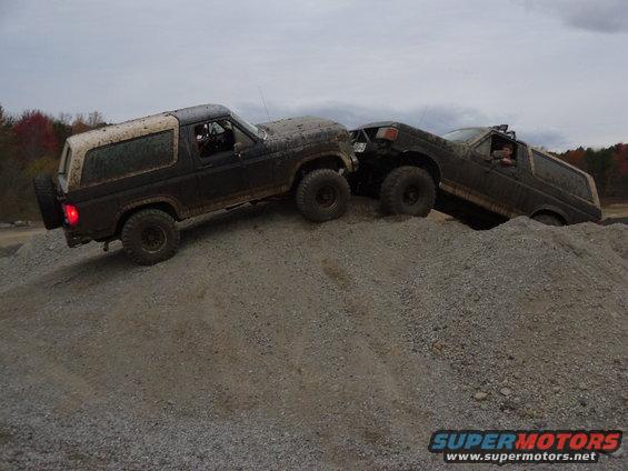 Two 1985 Ford Broncos climbing a steep gravel hill, one behind the other