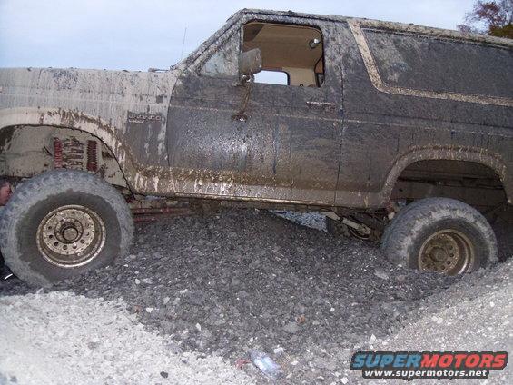 Muddy SUV stuck on gravel pile, side view
