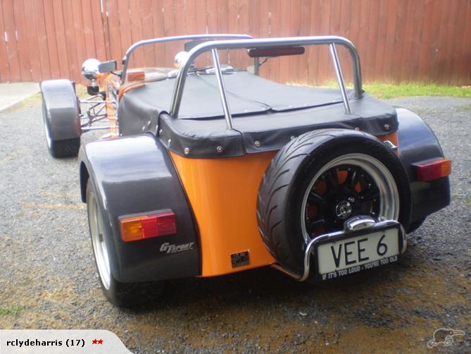 Rear view of orange and black kit car with spare tire and VEE 6 license plate