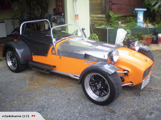 orange and silver sports car with black soft top and roll bar