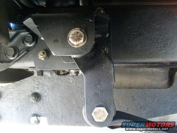 Black metal suspension part with hex bolts attached to a vehicle frame