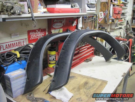 Black fender flares on a workbench with tools and supplies