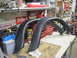 2005 Ford Excursion - Fender flares are displayed on a workbench in a garage setting, surrounded by various tools and automotive parts.