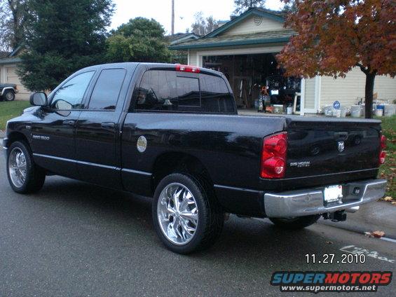 Black Dodge Ram pickup truck with chrome wheels, rear 3/4 view